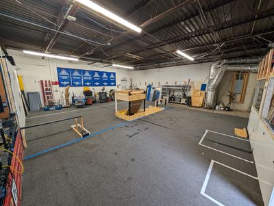 The empty practice field, with taped field markings, wooden field element mockups, and award banners on the far wall.